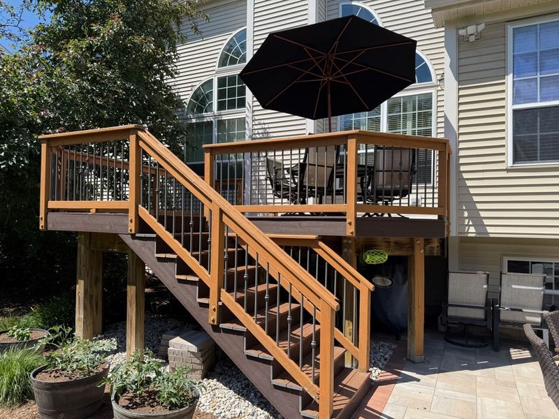 A finished deck with stairs: cedar-stained wood and black metal balusters